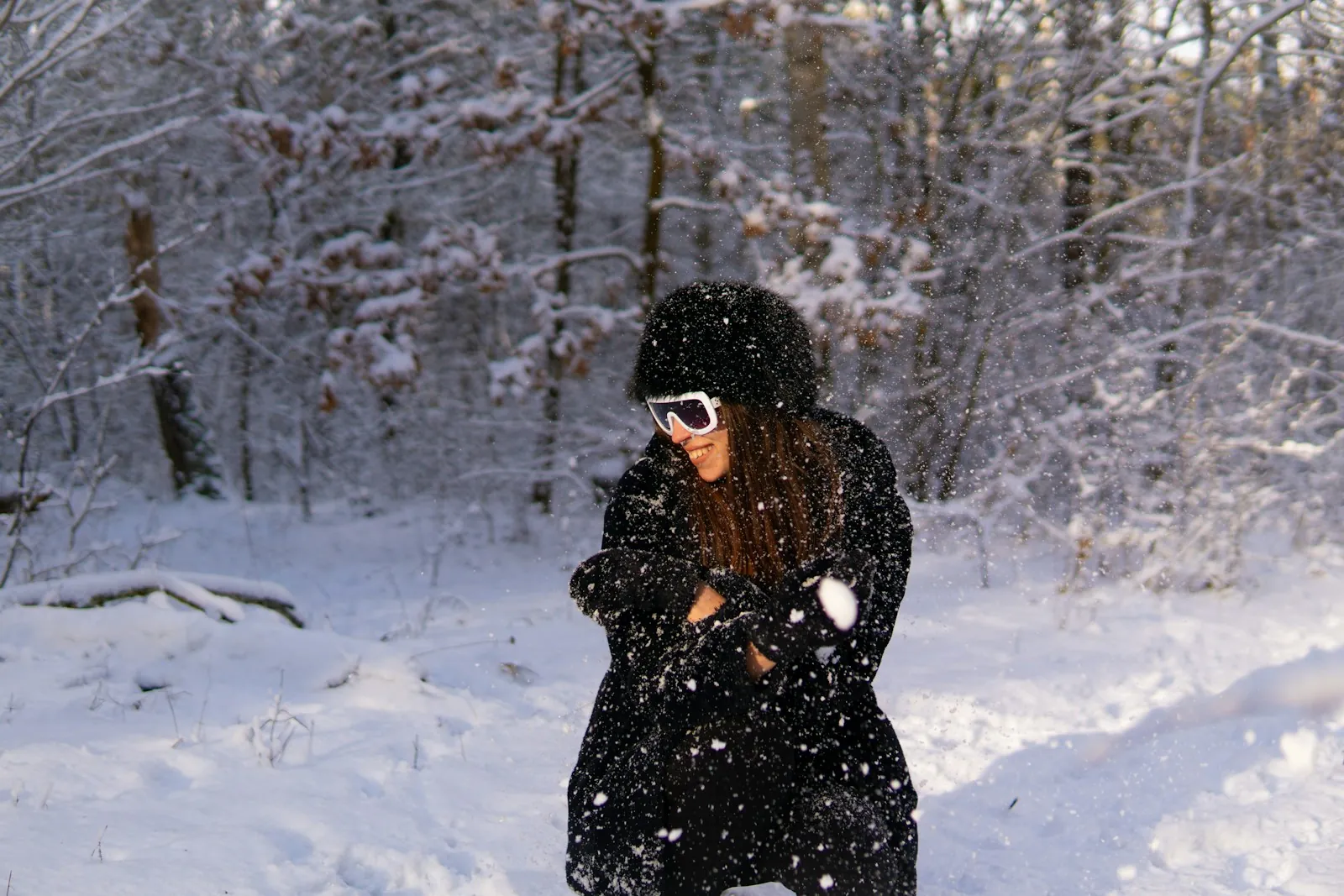 A woman in a warm winter coat and ski goggles in a snowy forest